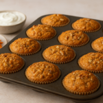 Muffins moelleux aux carottes, flocons d'avoine et fromage blanc disposés dans un moule à muffins, avec carottes râpées et bol de fromage blanc en arrière‑plan