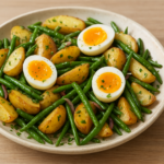 Salade tiède de pommes de terre rôties, haricots verts et œufs mollets coupés avec jaune coulant, persil ciselé